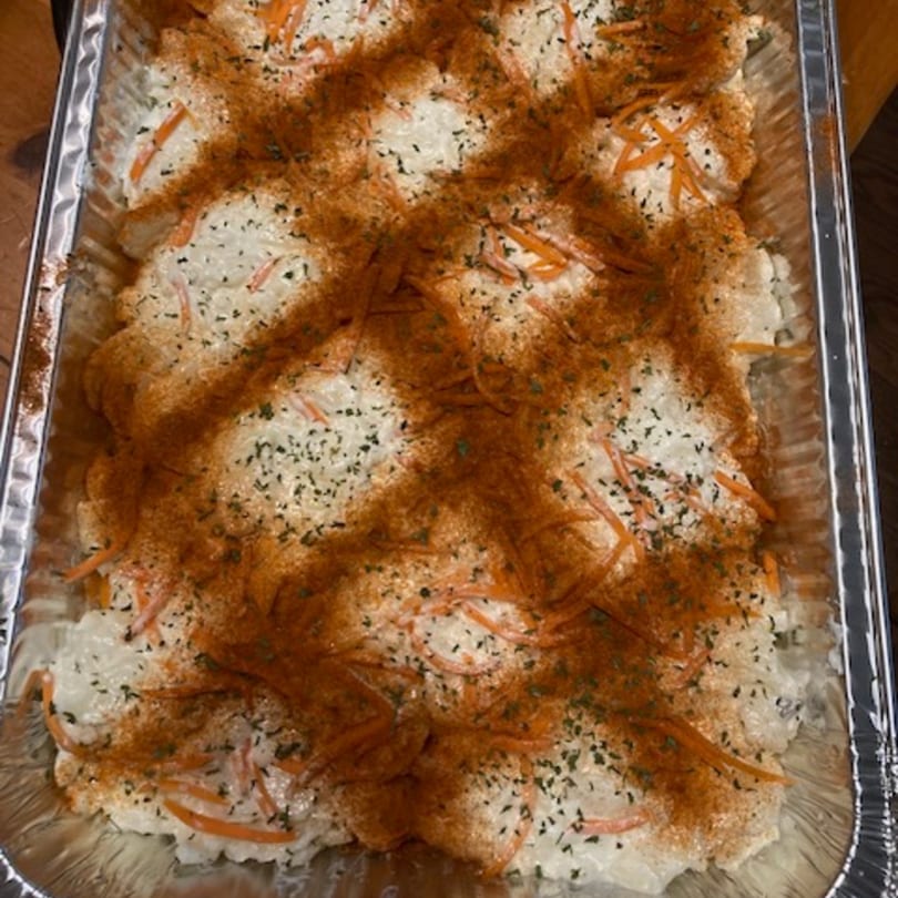 Creamy mac and cheese with shredded carrots, paprika, and herbs in a foil pan.